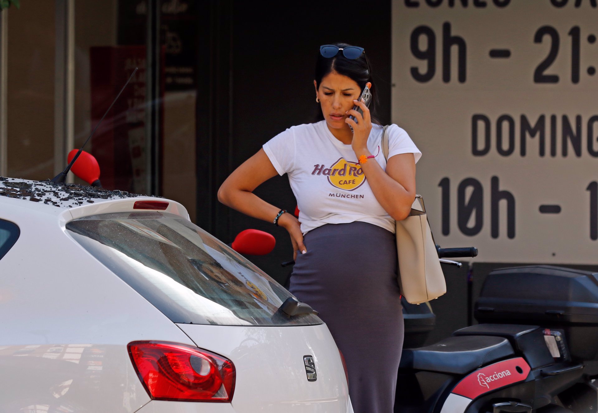 Gabriela, observando su coche mientras habla por teléfono