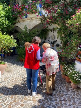 Una persona mayor acompañada de una voluntaria de Cruz Roja