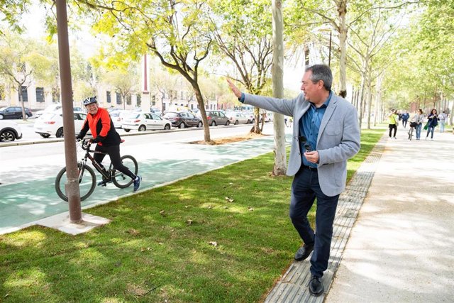 El secretario general del PSOE-A, Juan Espadas, saluda a un ciclista en el Paseo de Torneo de Sevilla.