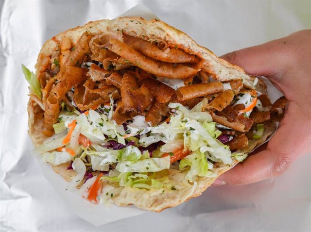 Archivo - FILED - 19 February 2018, Brandenburg, Frankfurt an der Oder: A person holds a Doner Kebab. Survey: Doner kebab topples currywurst as Germany's ruling fast food. Photo: Patrick Pleul/dpa-Zentralbild/ZB