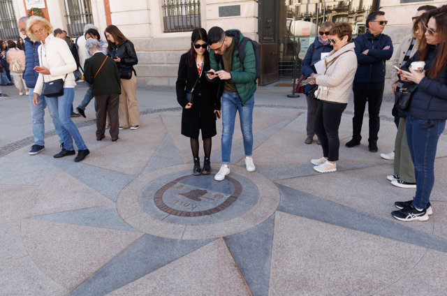 Dos personas pisan la placa del Kilómetro Cero, en la Puerta del Sol, a 4 de abril, en Madrid (España).