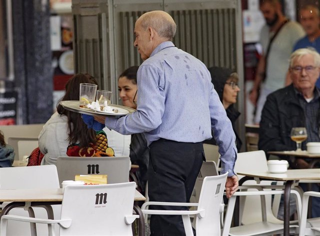 Archivo - Un camarero porta una bandeja en una terraza de un bar.