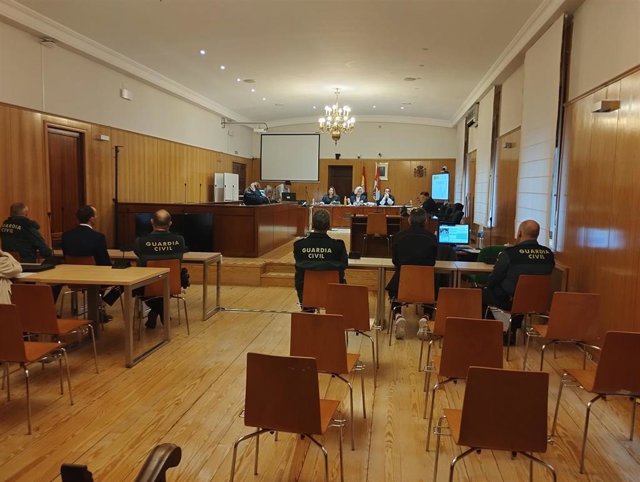 Los dos acusados, de espaldas y separados, custodiados por agentes de la Guardia Civil.