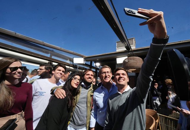 El presidente del PP, Alberto Núñez Feijóo, posa para una foto con jóvenes en un acto de vivienda en Madrid.