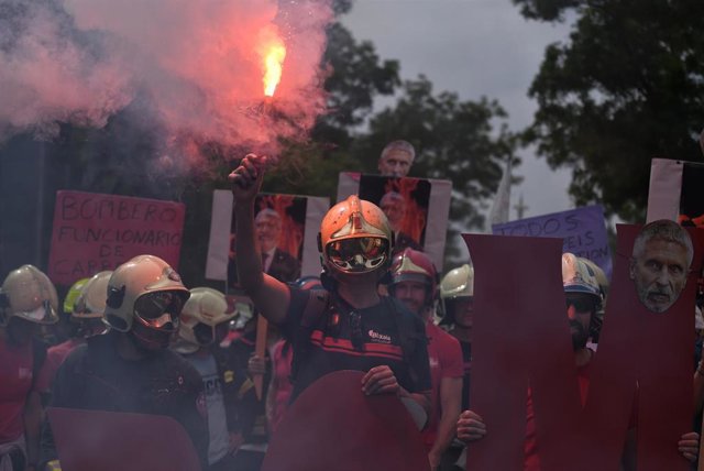 Un bombero sujeta una bengala de humo durante una manifestación de bomberos con fin en el Congreso de los Diputados, a 16 de mayo de 2023, en Madrid (España).