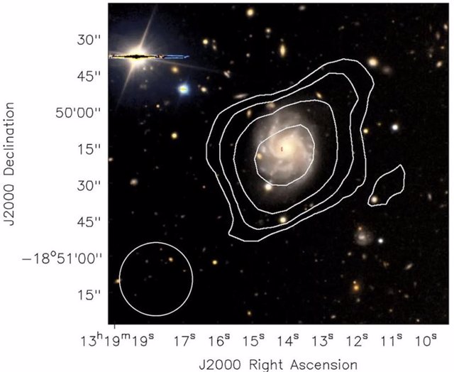 ASKAP encontró el gas de hidrógeno frío (contornos blancos) en esta galaxia espiral y señaló un FRB cerca del centro (ubicación dada por la elipse roja).