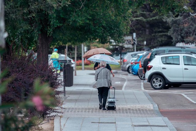 Varias personas pasean con paraguas, a 24 de mayo de 2023, en Madrid (España). 