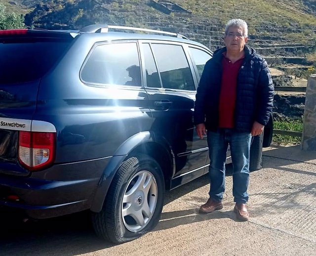 El candidato del PP de Olula de Castro (Almería) junto a su coche con las ruedas pinchadas.