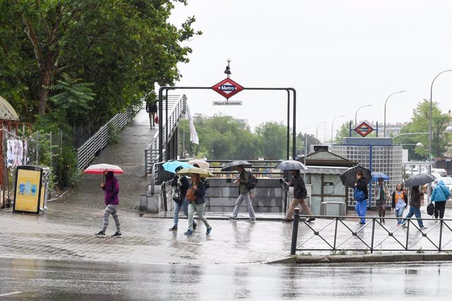 Varias personas pasean bajo la lluvia, en Madrid (España).