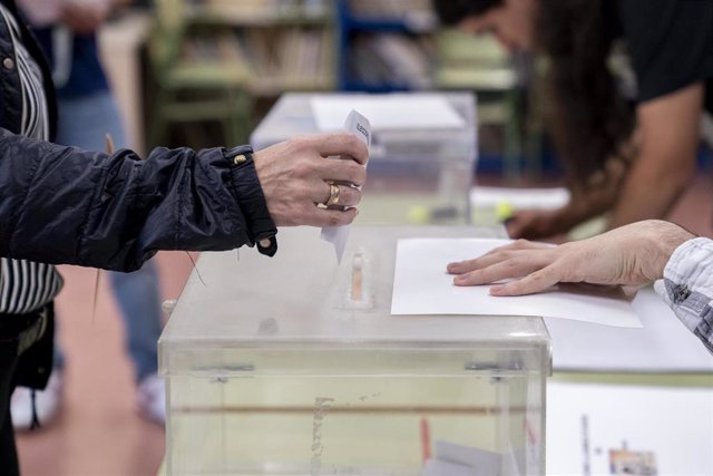 Una persona mete su voto en la urna en un colegio electoral