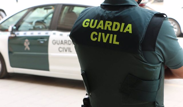 Archivo - Arquivo - Un axente da Garda Civil, de costas, xunto a un vehículo oficial