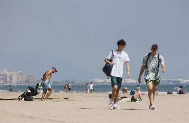 Archivo - Varias personas caminan por la playa de la Malvarrosa