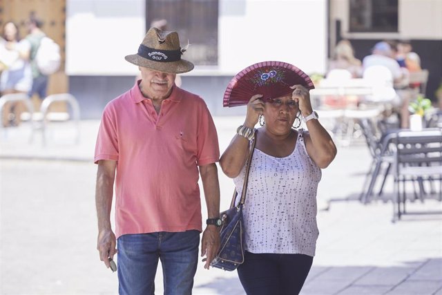 Archivo - Una señora se protege con el abanico del sol mientras el hombre lo hace con un sombrero en el primer día de la segunda ola de calor, a 7 de julio de 2022 en Sevilla (Andalucía, España) (Foto de archivo).
