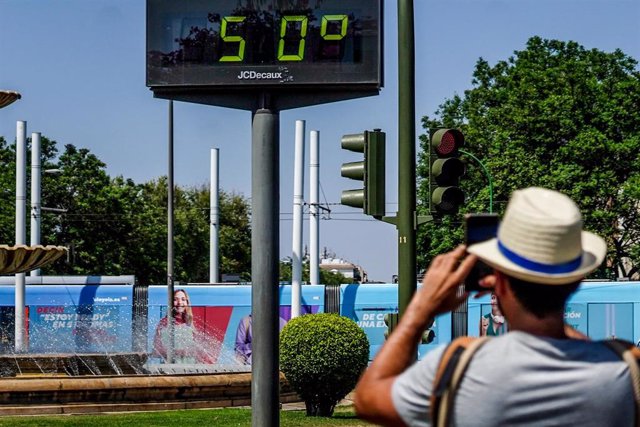Transeúntes fotografían el termómetro situado en el Prado que marca 50 grados.
