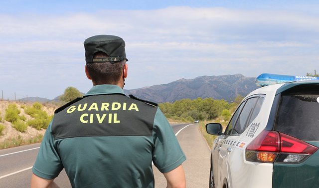 Archivo - Un agente de la Guardia Civil junto a un vehículo en una carretera.