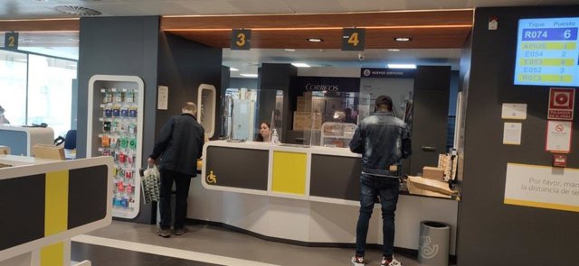 Dos ciudadanos son atendidos en una oficina de corrreos.