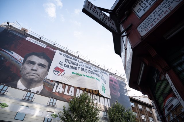 Una nueva lona desplegada por el Movimiento de Vivienda de Madrid encima del cartel de Desokupa, donde se lee ‘Ni alquileres, ni hipotecas, ni deudas. Vivienda gratuita, universal, de calidad y bajo control obrero’.