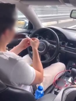 Un conductor se lía un cigarrillo con ambas manos mientras sujeta el volante con las rodillas en la A-7.
