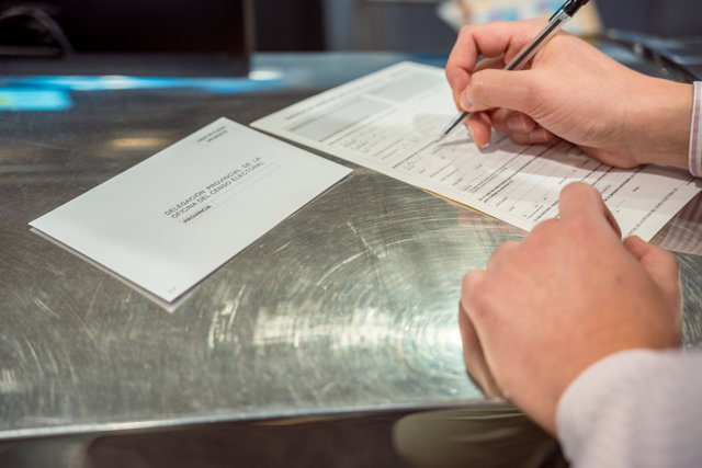 Una persona rellena unos documentos tras solicitar el voto por correo en el Edificio de correos, a 14 de junio de 2023, en Madrid (España). 