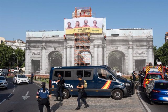 Un vehículo y agentes de Policía Nacional delante de una lona colgada por Greenpeace en la Puerta de Alcalá, a 11 de julio de 2023, en Madrid (España). 