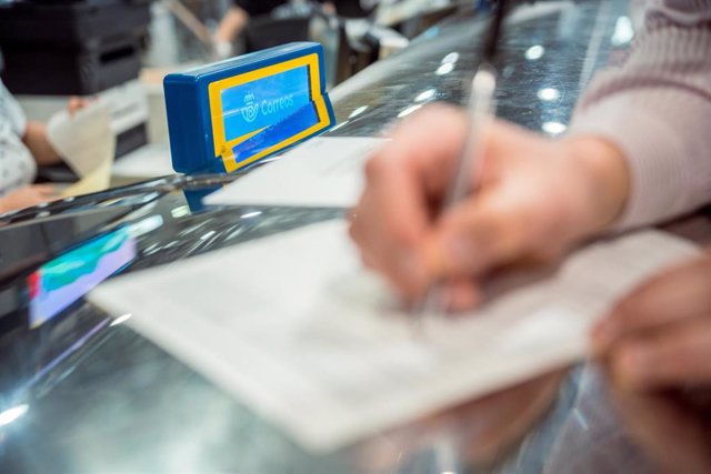 Una persona rellena unos documentos tras solicitar el voto por correo en el Edificio de correos, a 14 de junio de 2023, en Madrid (España).