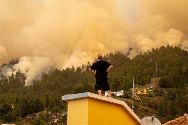 Un vecino observa desde el tejado de una casa el incendio forestal declarado en  la Palma, cerca de una vivienda, a 15 de julio de 2023, en Puntagorda, La Palma, Canarias (España). Este incendio declarado en la madrugada de hoy en zona urbano forestal en 