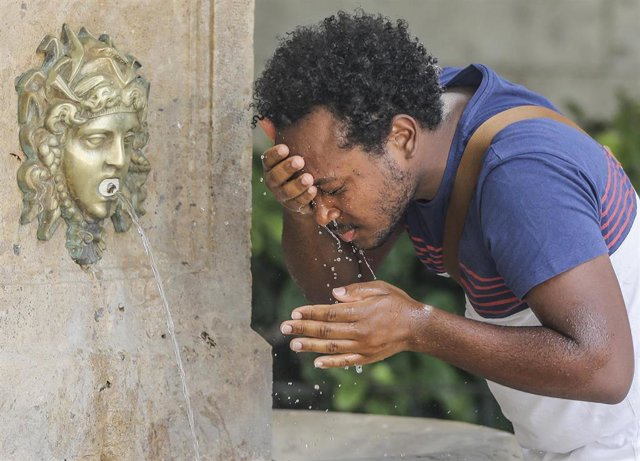 Archivo - Un hombre se refresca en una fuente (archivo)