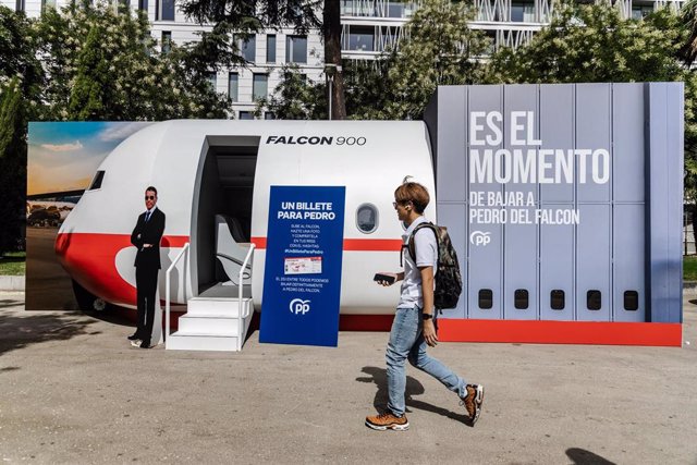 Una persona camina frente a la maqueta del avión Falcon 900 en la calle Recoletos, a 19 de julio de 2023, en Madrid (España). El Partido Popular ha colocado esta maqueta, del avión del ejército que el presidente del Gobierno y Casa Real utilizan para algu