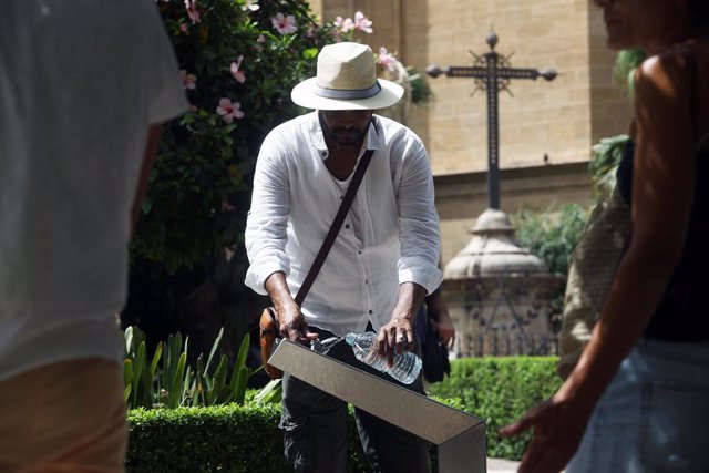 Un hombre rellena una botella de  agua de una fuente para combatir  la ola de calor