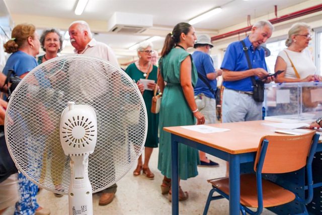 Archivo - Electores votando en un colegio de Sevilla con un ventilador para hacer frente al calor