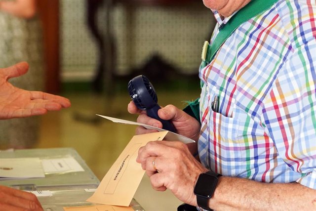 Una persona con un ventilador portatil ejercen su derecho a voto 