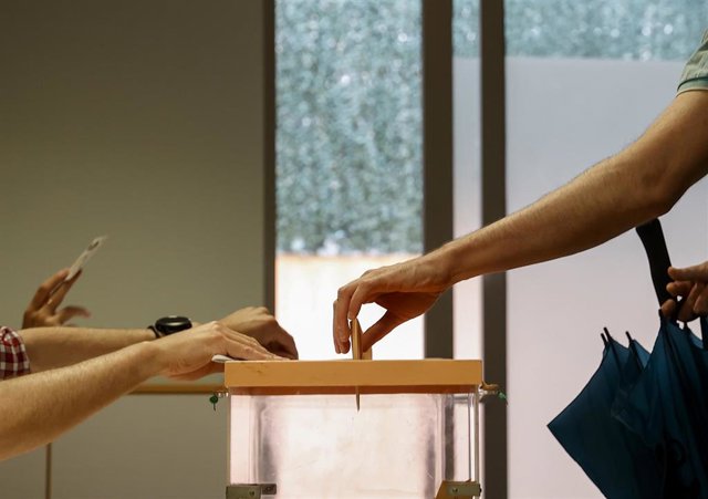 Archivo - Una persona mete su voto en una urna
