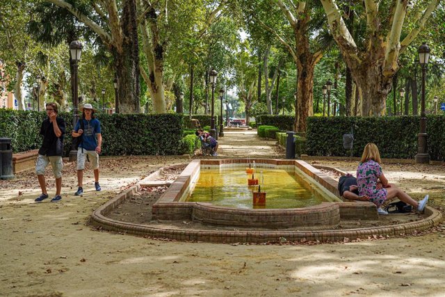 Una pareja descansa  y otros pasean por los Jardines del Cristina el día en que Sevilla está en alerta naranja por el calor , a 19 de julio del 2023. (Foto de archivo).