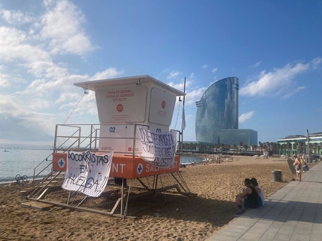 Un punt de vigilància dels socorristes de Barcelona a la platja de la Barceloneta amb pancartes reivindicatives