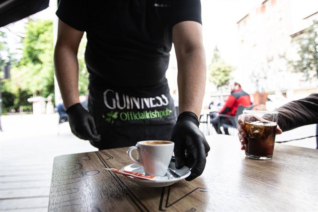 Archivo - Un camarero sirve un café en una terraza en el centro de Vitoria (Álava)