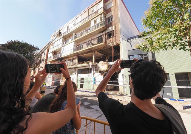 Varias personas toman fotografías del inmueble en el que sucedió el incendio por una explosión de gas, en la calle Goya de Valladolid.