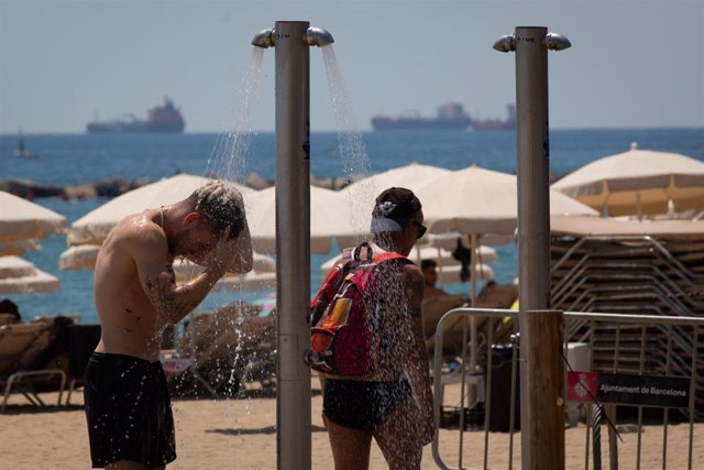 Bañistas en las duchas de la playa de Málaga 