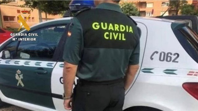Archivo - Un agente de la Guardia Civil junto a su vehículo.