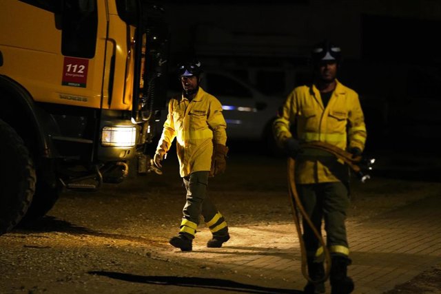 Dos agentes del INFOCA salen del fuego, ya controlado por la noche, a 06 de agosto del 2023 en Puerto Real (Cádiz, Andalucía). 