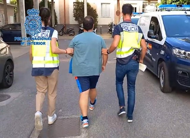 El detenido es conducido por agentes al vehículo de la Policía.