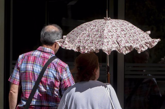 Imagen de archivo de una mujer protegiéndose del calor con un paraguas.  