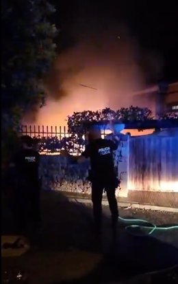 Agentes de la Policía Local de Alcúdia intentan sofocar las llamas con unas mangueras.