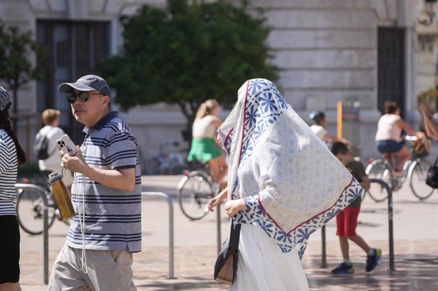 Dos personas caminan por la calle durante la cuarta ola de calor del verano, a 22 de agosto de 2023.