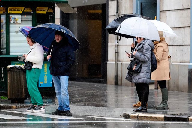 Archivo - Un grupo de personas con paraguas en un paso de cebra en Santander.- Archivo