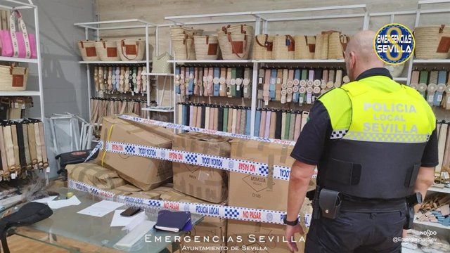 Un agente de la Policía Local ante los artículos falsificados intervenidos en la operación.