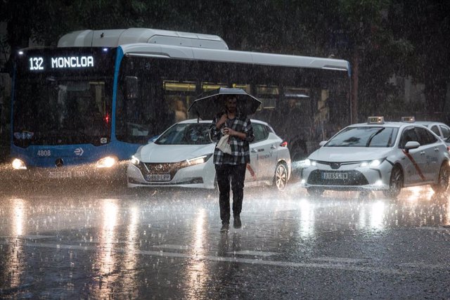 Archivo - Una persona cruza la calle bajo la lluvia, en Madrid (España).