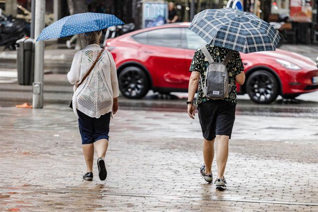 Dos personas caminan bajo la lluvia, archivo 