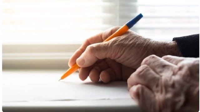 Unas manos de una persona mayor escribiendo.