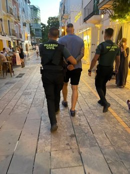 Dos agentes de la Guardia Civil llevan esposado al detenido.