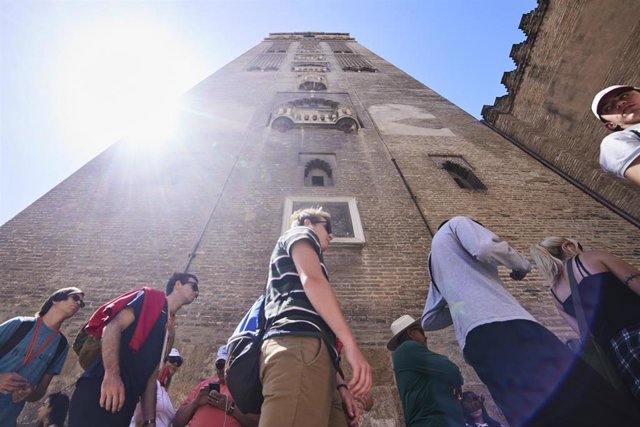 Archivo - Turistas hacen cola bajo la Giralda para entrar a la visita de la Catedral de Sevilla, en una foto de archivo.